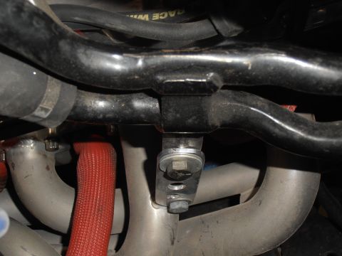 1990 Ford Bronco - Detail of engine parts, including hoses and exhaust manifold components, with visible text on a black hose.