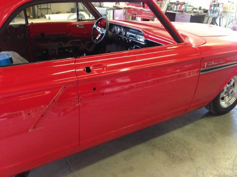 1964 Ford Fairlane - The interior of a red 1964 Ford Fairlane is visible, with the driver's side door panel removed for work.