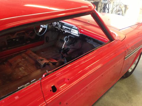 1964 Ford Fairlane - Interior view of a red 1964 Ford Fairlane undergoing restoration, showing exposed floor panels and dashboard.