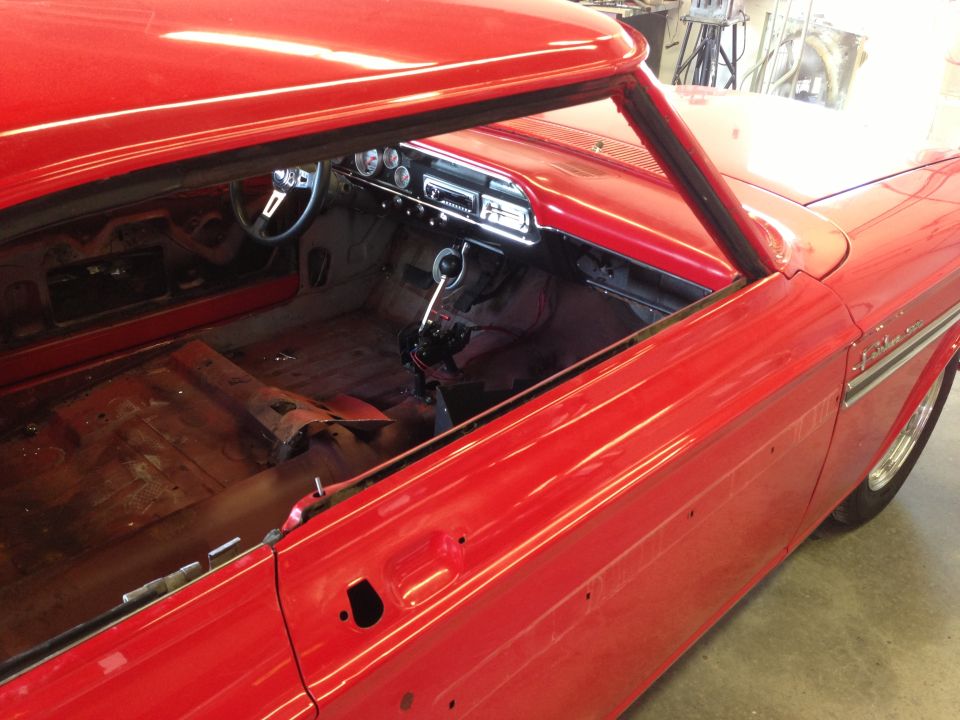 Red 1964 Ford Fairlane interior with bare metal floor, dashboard gauges, and steering wheel visible