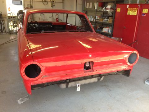 1964 Ford Fairlane - Front view of a red 1964 Ford Fairlane in a workshop, appearing to be undergoing restoration with new paint and interior work.