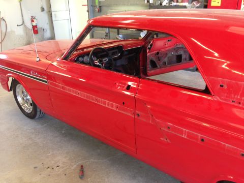 1964 Ford Fairlane - A red coupe, possibly a Fairlane, is in a workshop with its doors removed, revealing the interior and unfinished bodywork.