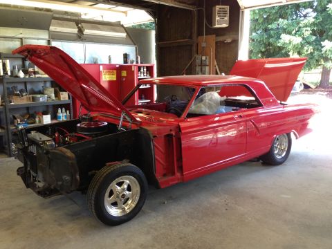 1964 Ford Fairlane - A red 1964 Ford Fairlane is shown with its hood and trunk open, revealing the engine and interior in a garage setting.