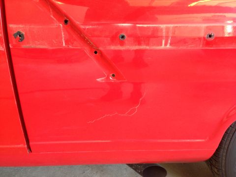 1964 Ford Fairlane - Close-up of a red car's side panel showing paint imperfections and mounting points.
