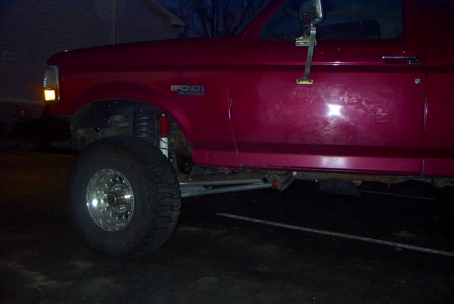 Side view of a red 1994 Ford Bronco with large tires