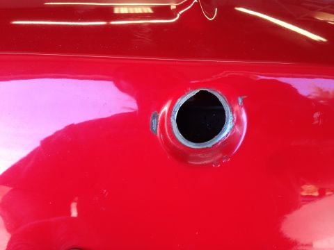 1964 Ford Fairlane - The fuel filler opening on a red vehicle shows exposed metal around the edge.