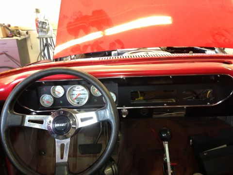 1964 Ford Fairlane - Interior view of a red car with aftermarket gauges and a Grant steering wheel.