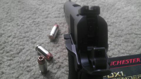 2000 Mercury Grand Marquis - A black pistol rests on a carpeted surface next to three bullets, with a Winchester box partially visible.