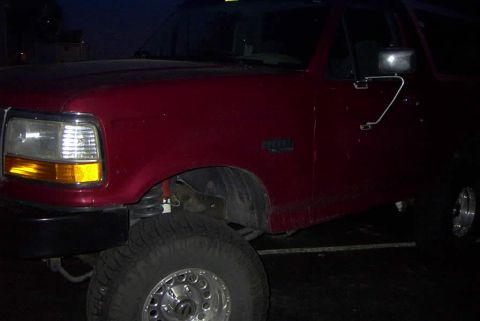 1994 Ford Bronco - A red Ford Bronco is viewed from the front 3/4 angle at night.