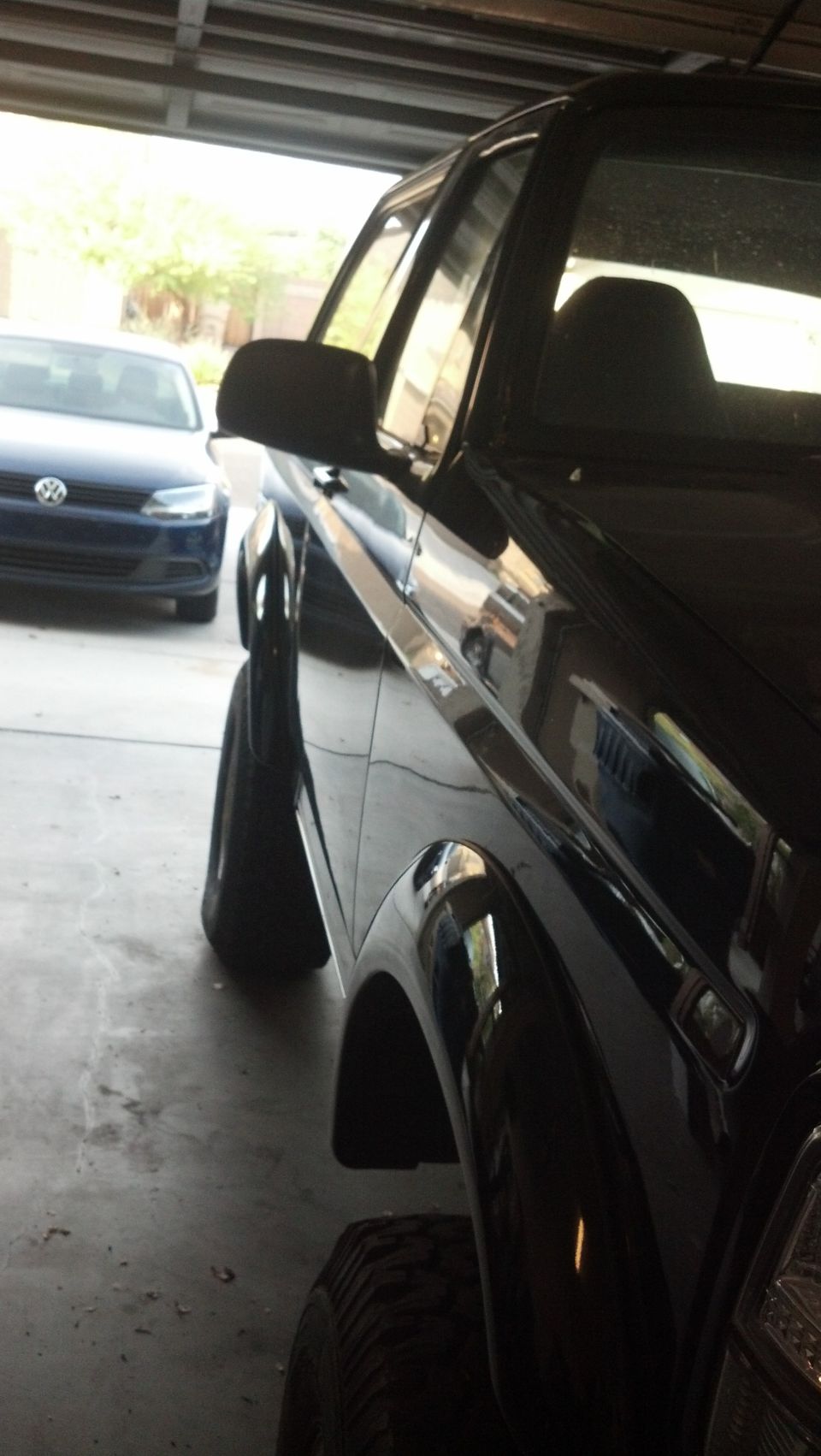 Black SUV with lifted suspension, seen from the front quarter angle in a garage