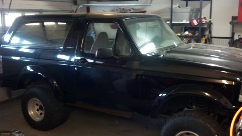 1995 Ford Bronco - This black SUV, likely a 1992 model, is viewed from the front three-quarter angle inside a garage.