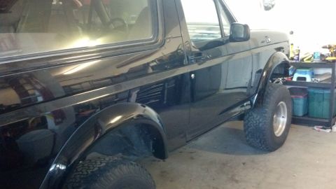 1995 Ford Bronco - Side profile of a black 1995 Ford Bronco, showing its distinctive body style and large tires.