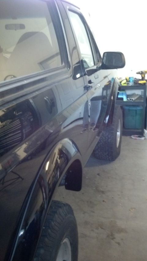 1995 Ford Bronco - Side profile of a black 1995 Ford Bronco, parked indoors with tools in the background.