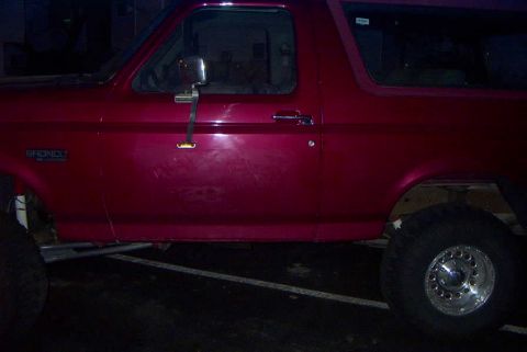 1994 Ford Bronco - Side profile of a red 1994 Ford Bronco, showing the 'BRONCO' badge on the fender.