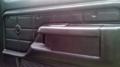 1979 Ford Bronco - Close-up of a vehicle's interior door panel, showing textured material and an armrest.