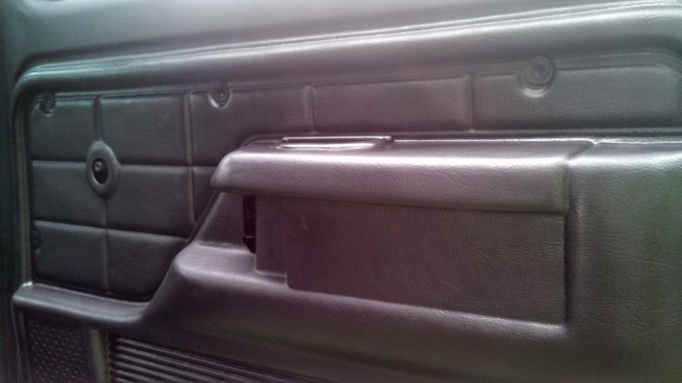 Black interior door panel with armrest and window crank hole