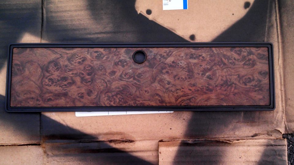 Wood grain dashboard trim piece with a central circular cutout