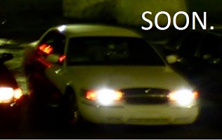 2000 Mercury Grand Marquis - A white sedan is seen from the front at night, with the word 'SOON.' displayed prominently.
