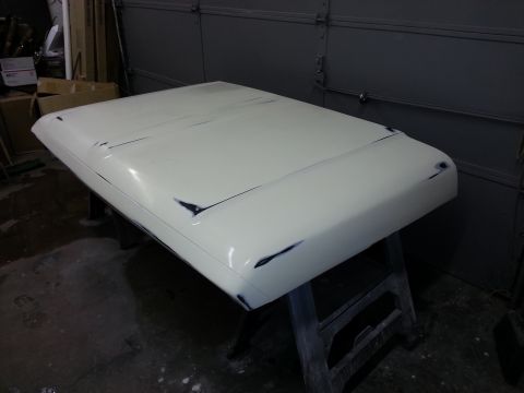 1967 Ford F-100 - A white 1967 Ford F-100 hood is prepped for paint, resting on sawhorses in a garage.
