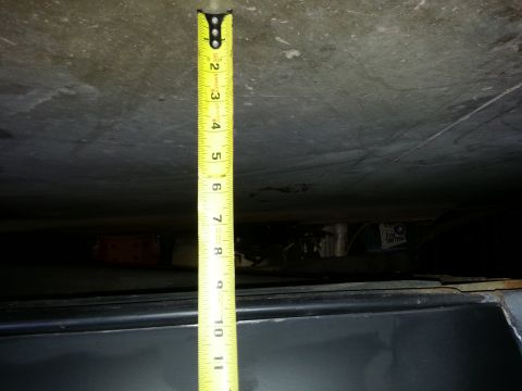 1967 Ford F-100 - A yellow measuring tape is used to gauge the clearance under a vehicle component.