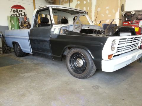 1967 Ford F-100 - This 1967 Ford F-100 pickup is in a garage, showing primer and black paint on its body panels during restoration.