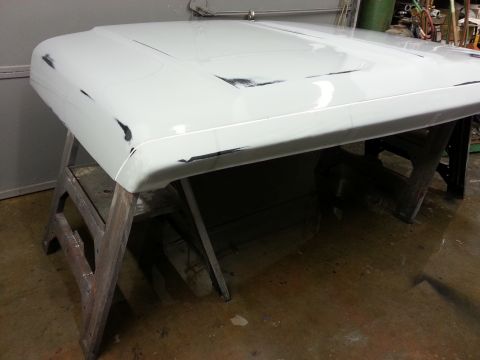 1967 Ford F-100 - A truck hood is prepped for paint, resting on wooden sawhorses in a workshop.