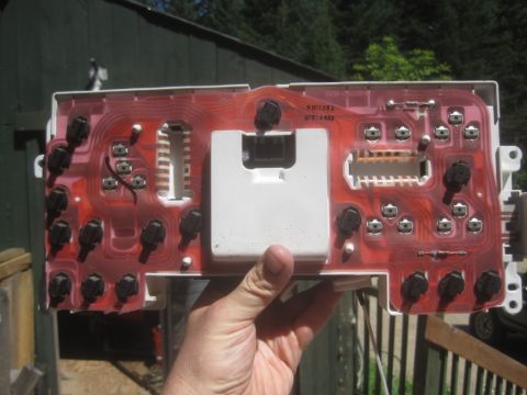 1993 Ford Bronco - The back of a vehicle's instrument cluster circuit board is held by a hand.