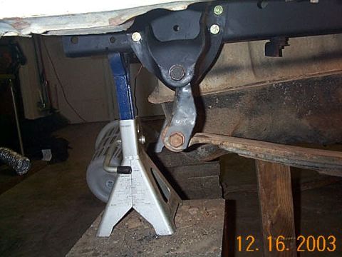1986 Ford Bronco - Close-up view of vehicle suspension components and frame, supported by jack stands.