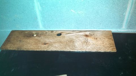 1979 Ford Bronco - A wooden plank rests on a black surface against a blue cinder block wall.