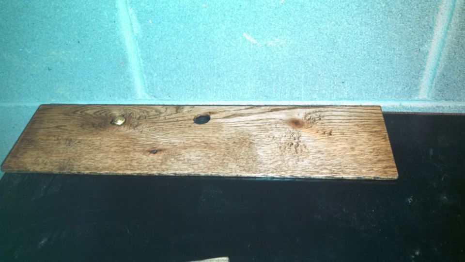 wooden plank with two holes and a nail