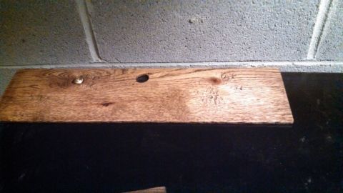 1979 Ford Bronco - A wooden plank is shown against a cinder block wall, with a visible nail and two holes.