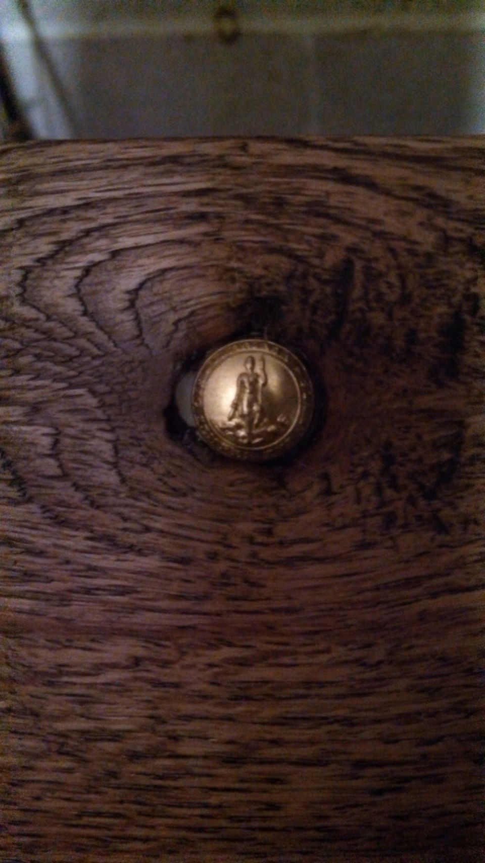 Gold emblem with figure on wood grain texture