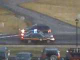 1979 Ford Bronco - A dark SUV is seen from behind driving on a wet road, with another vehicle partially visible.