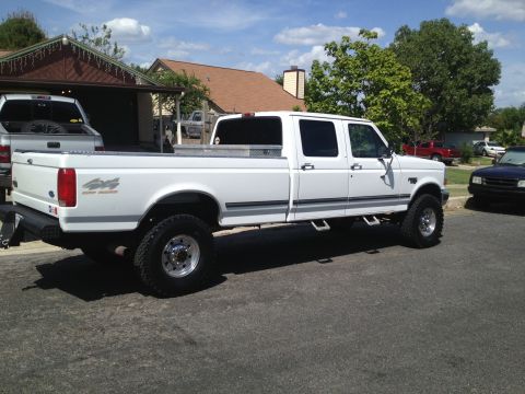 1997 Ford F-350 - A white 1997 Ford F-350 crew cab pickup truck is seen from the side, parked on a street with houses in the background.