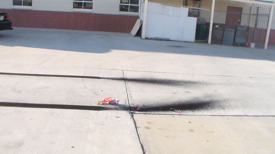 Concrete lot with firework debris and burn marks beside a building