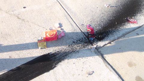 2003 Ford Crown Victoria - Burnt firework boxes and colorful wrappers lie on cracked concrete amid dark scorch streaks.