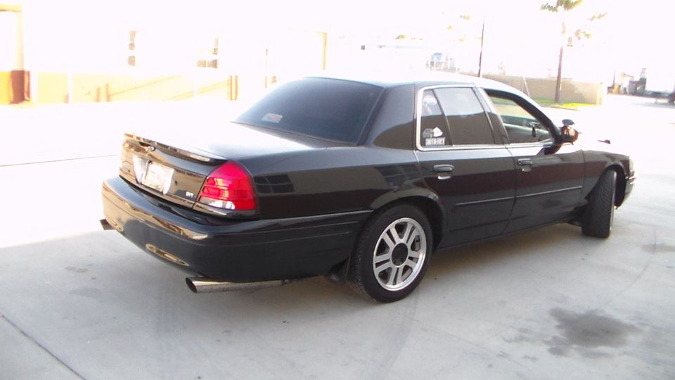 Rear three-quarter view of a black full-size sedan with alloy wheels on pavement