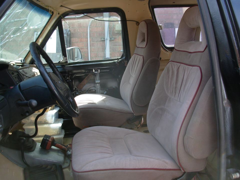 Truck interior front seats in tan cloth with red piping and a worn dash