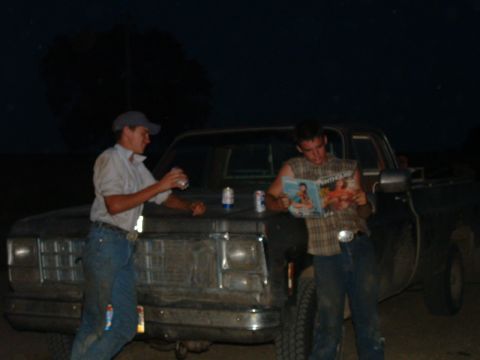 1988 Ford F-150 - Two men are standing next to a pickup truck at night, one holding a drink and the other reading a magazine.