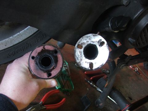 2008 Yamaha Zuma - Two exhaust pipe ends are shown, one being held by a hand, with tools scattered around.