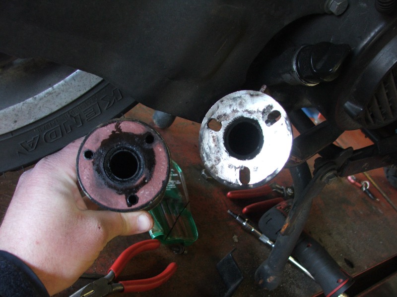 holding two exhaust pipe ends, one with pink gasket, next to a tire and tools