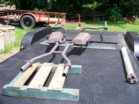 1999 Mercury Grand Marquis - A trailer carries an exhaust system and a driveshaft, with a utility trailer in the background.