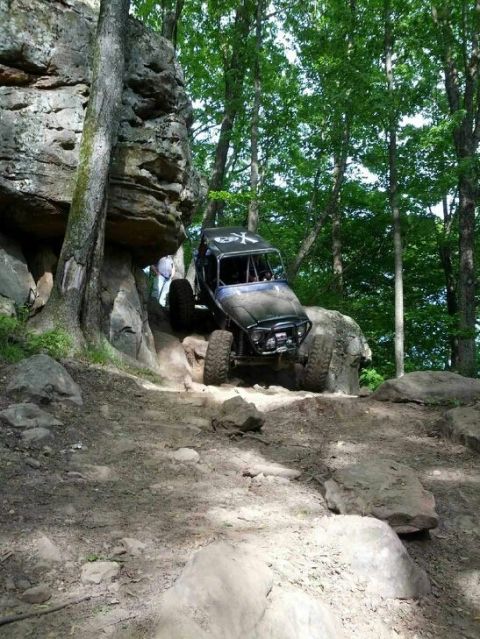 1967 Ford Mustang - Custom off-road buggy tackles a challenging rocky trail in a wooded area.