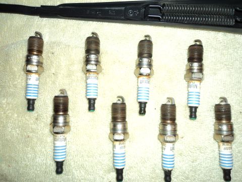 2004 Mercury Grand Marquis - A collection of Motorcraft spark plugs, some with visible part numbers, are arranged on a cloth surface.