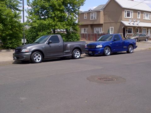 2003 Ford F-150 - Two Ford F-150 Lightning trucks are parked side-by-side on a residential street.