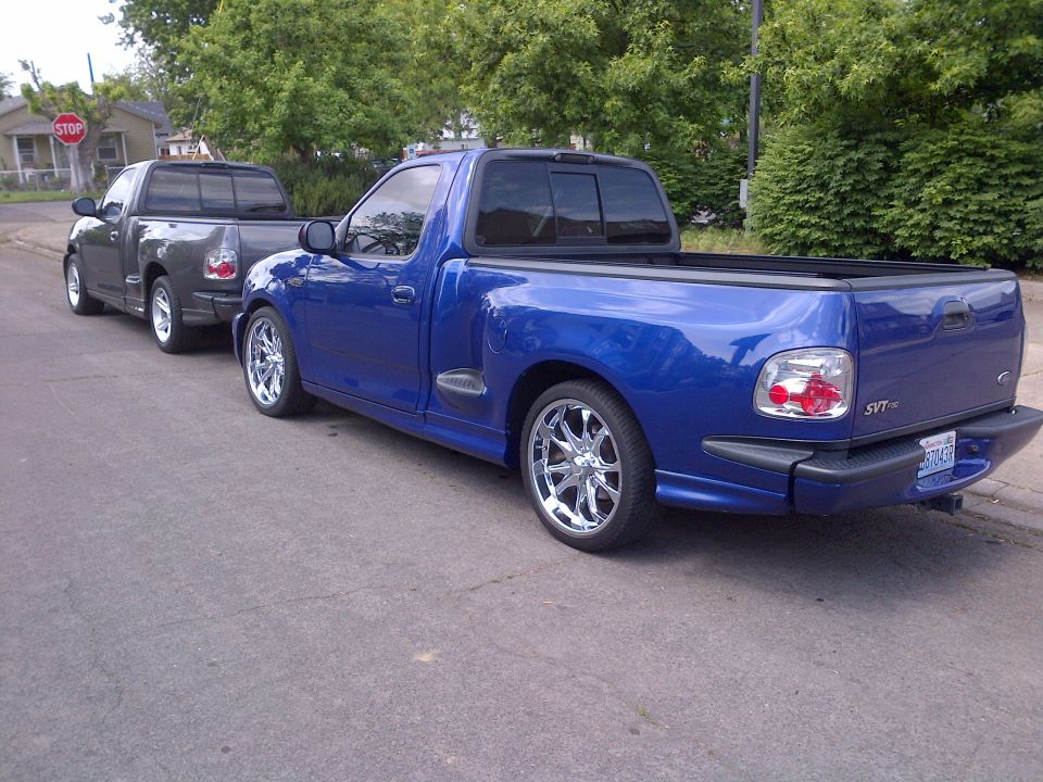 Blue 2003 Ford F-150 Lightning pickup truck with chrome wheels parked on a street