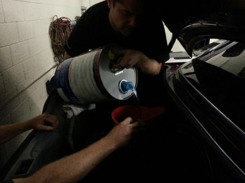 1992 Ford Crown Victoria - Fluid being poured into a car's trunk using a funnel.