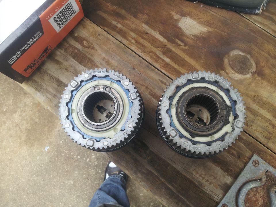 Two automatic locking hubs on a wooden surface, with a box and a tool nearby