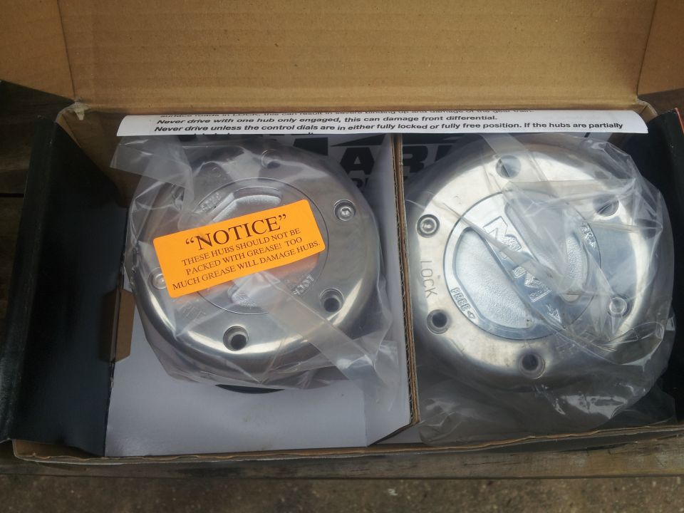 Two new manual locking hubs in a cardboard box, one with an orange notice sticker