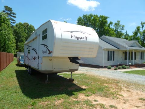 1992 Ford Mustang - A Flagstaff RV trailer is parked in the driveway of a suburban home on a sunny day.